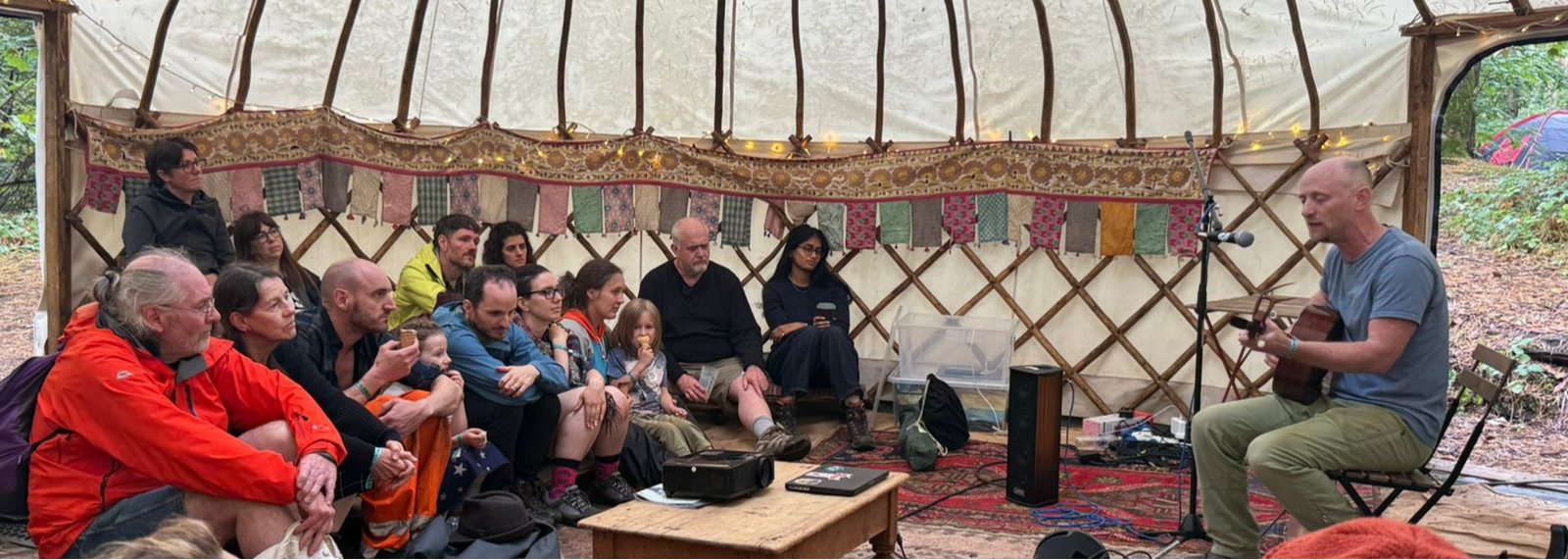 David Green playing The Kindling Songs to a seated circle in a yurt
